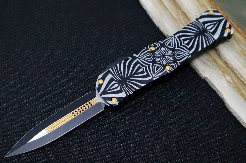 Microtech Hera "Source" Signature Series OTF - Dagger Style / Two-toned Black Blade with Gold Accents / Black Aluminum Handle with "Source" Artwork 702-TSOS